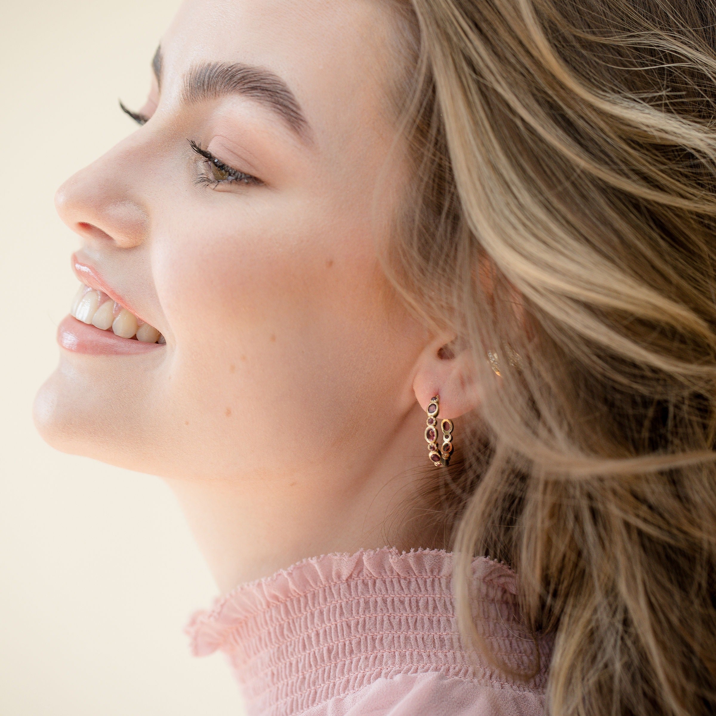 A close-up of a model wearing the gold pink tourmaline hoop earrings