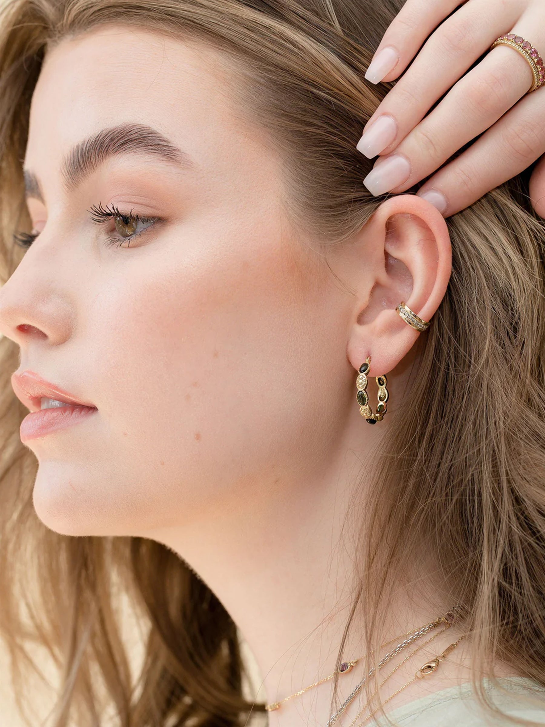 Close-up of a model wearing gold hoop earrings layering with a cuff earring.