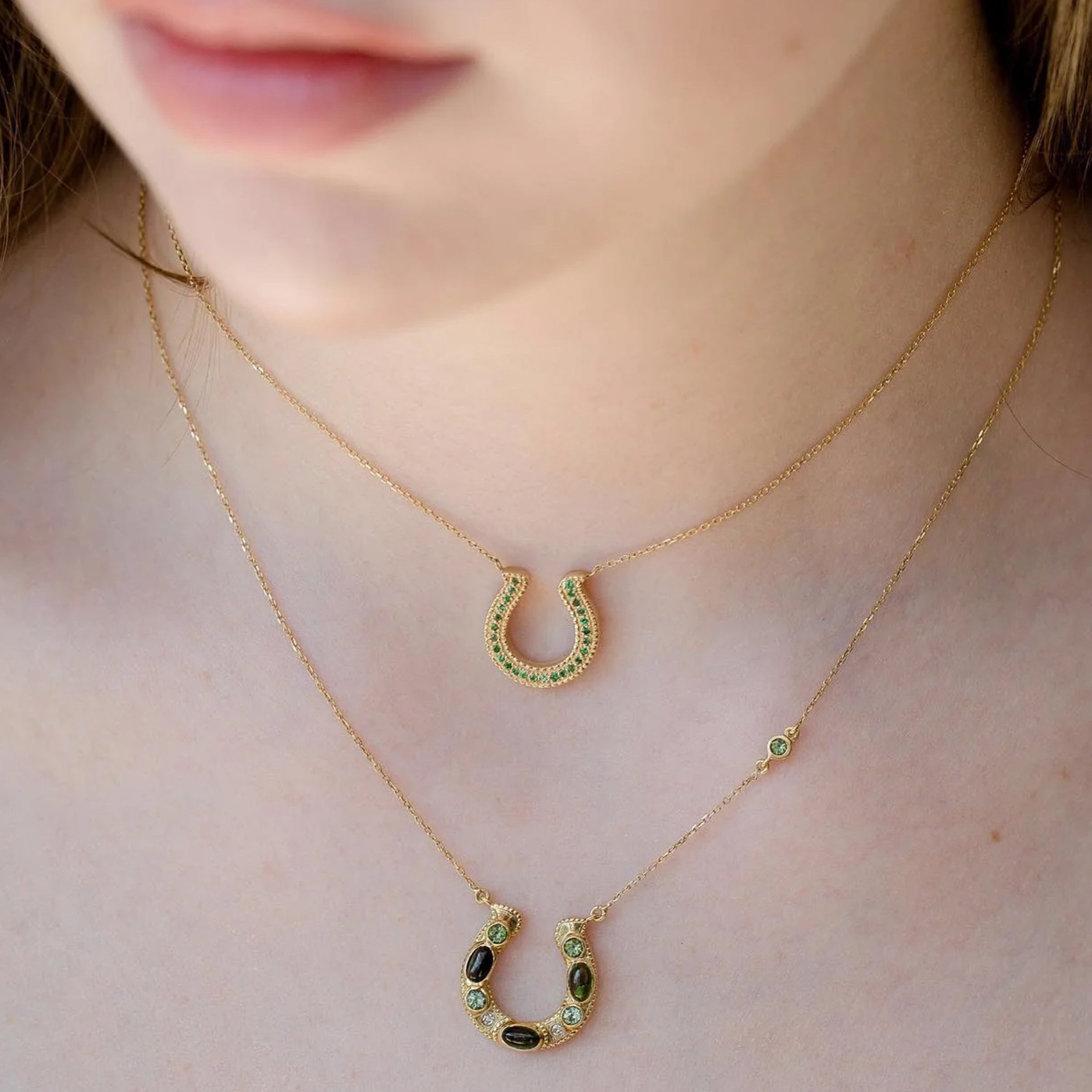 Horseshoe Tsavorite Necklace on model — 18k yellow gold, green tsavorite pavé, layered with second horseshoe, close-up front view