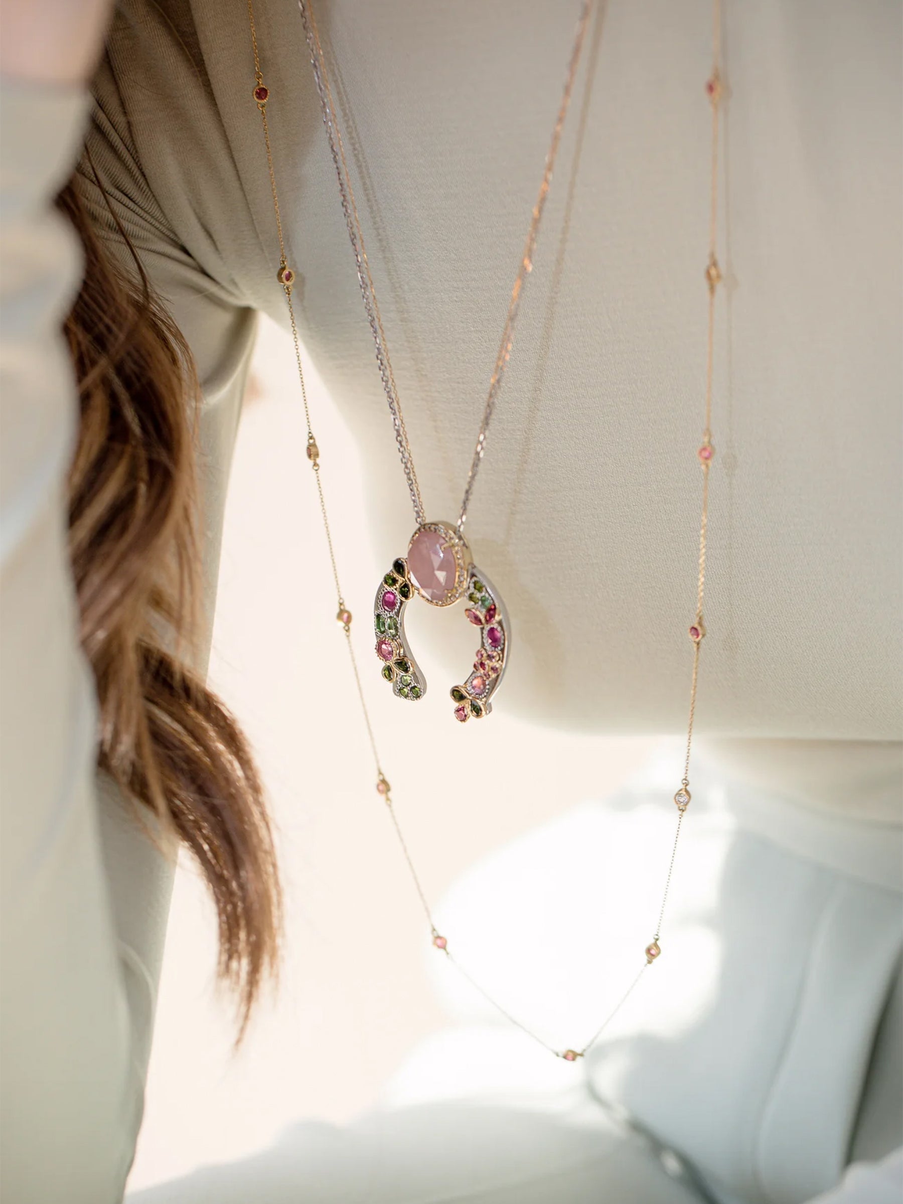 Model wearing the 18k gold Freestyle Pink Tourmaline Long Necklace layered with the Horseshoe Necklace, featuring round tourmaline stones and a diamond accent for a day-to-night look.