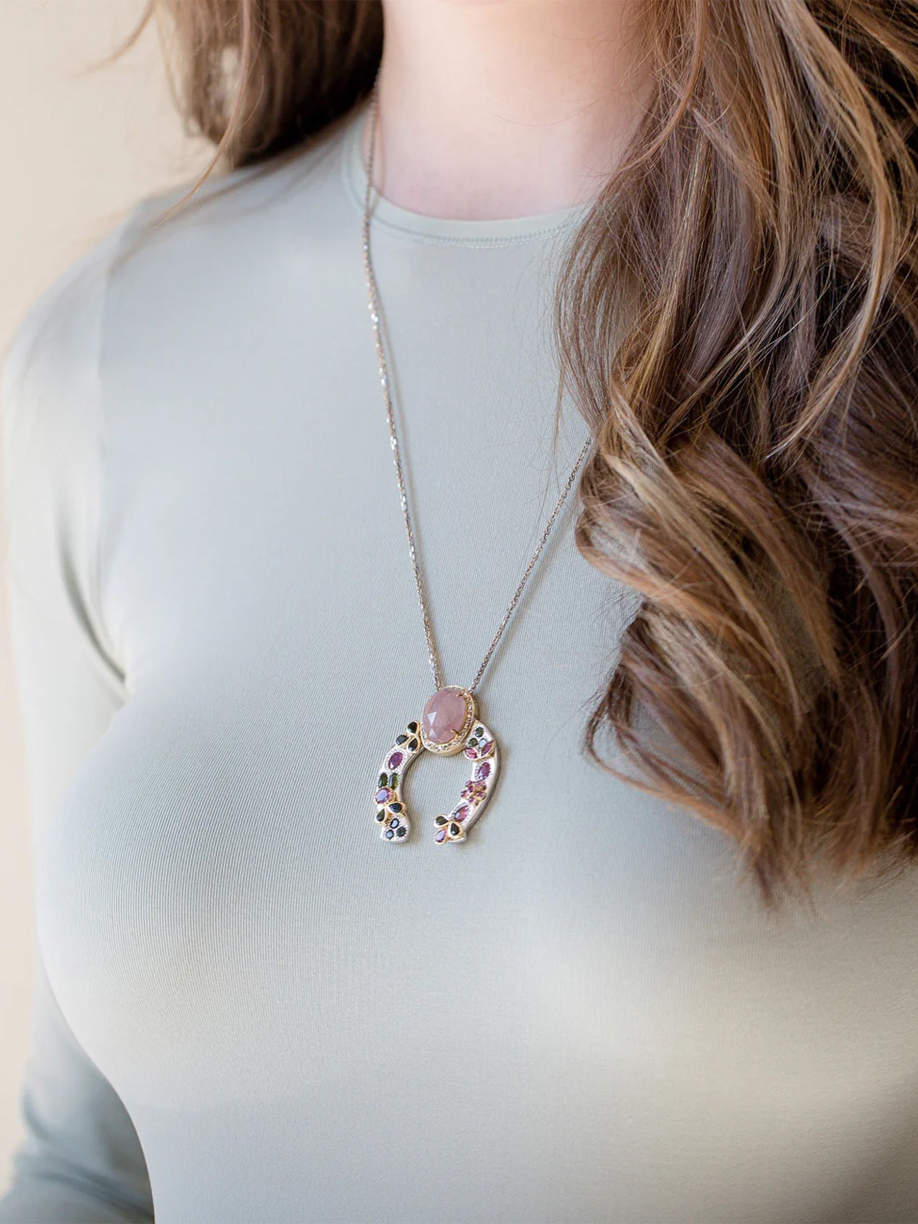 On-model view of the Horseshoe necklace featuring pink sapphire, tourmaline accents, diamond crown, and 14k gold leaf detailing on palladium- and rhodium-treated silver.