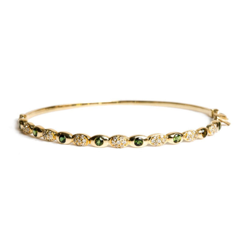 Gold bracelet with green tourmaline gemstones and diamonds on a white background