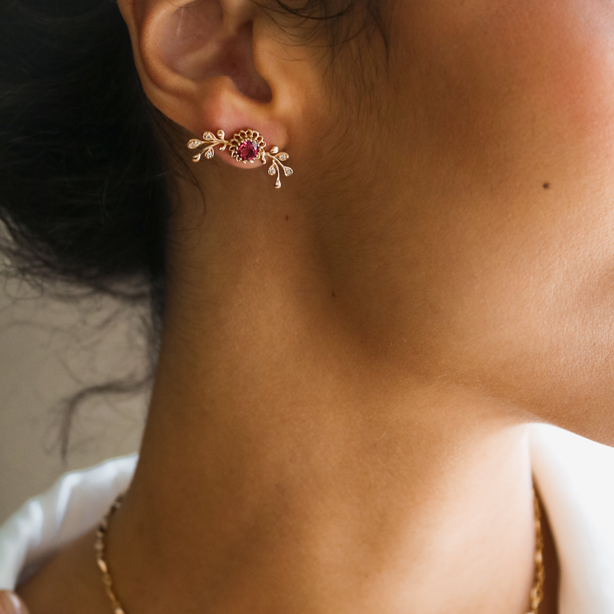A model wearing the Aghabani Gold Pink Tourmaline Lily Veins Earrings by Hania Kuzbari, highlighting the delicate gold branches, diamonds, and vibrant pink tourmaline gemstones