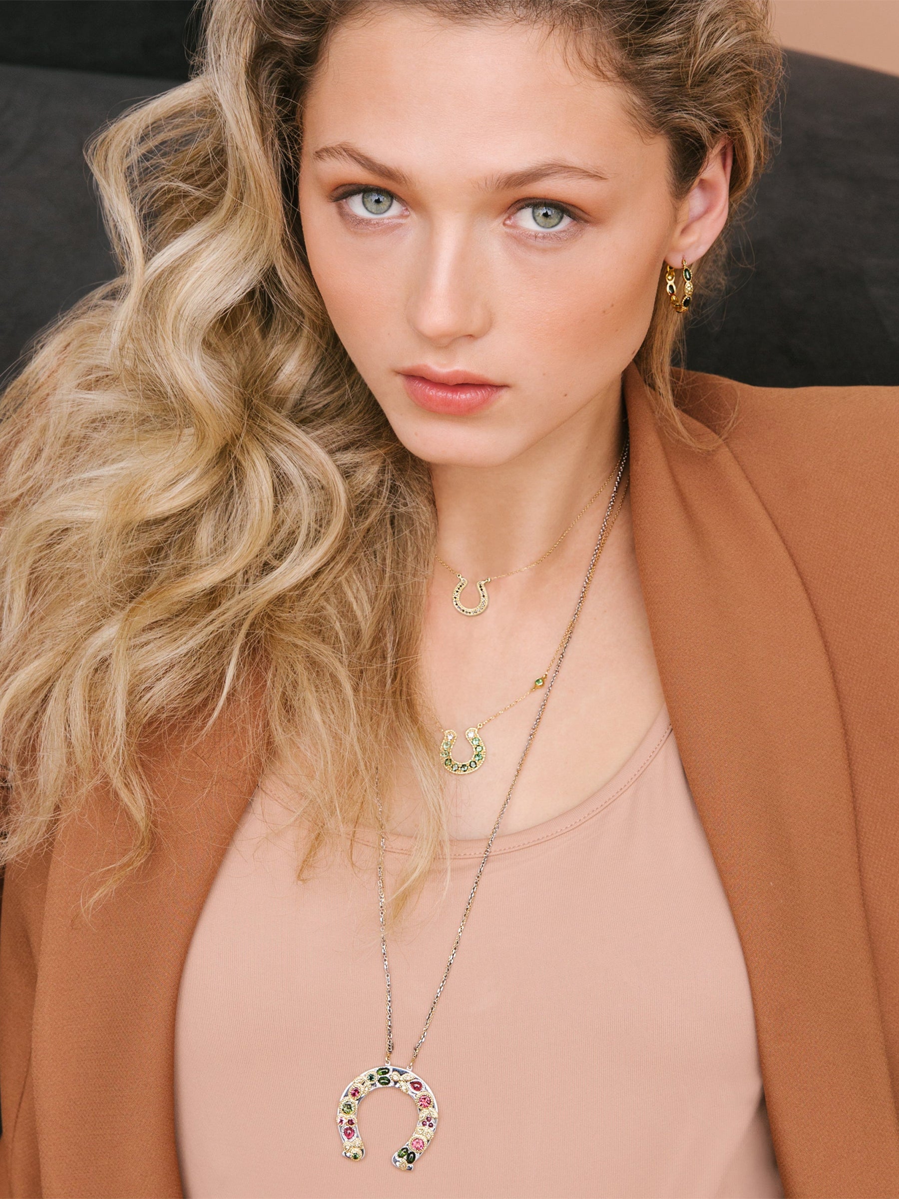18k Gold Horseshoe Necklace with Green Tourmaline Ombré Gradient on a model layered with horseshoe necklaces 