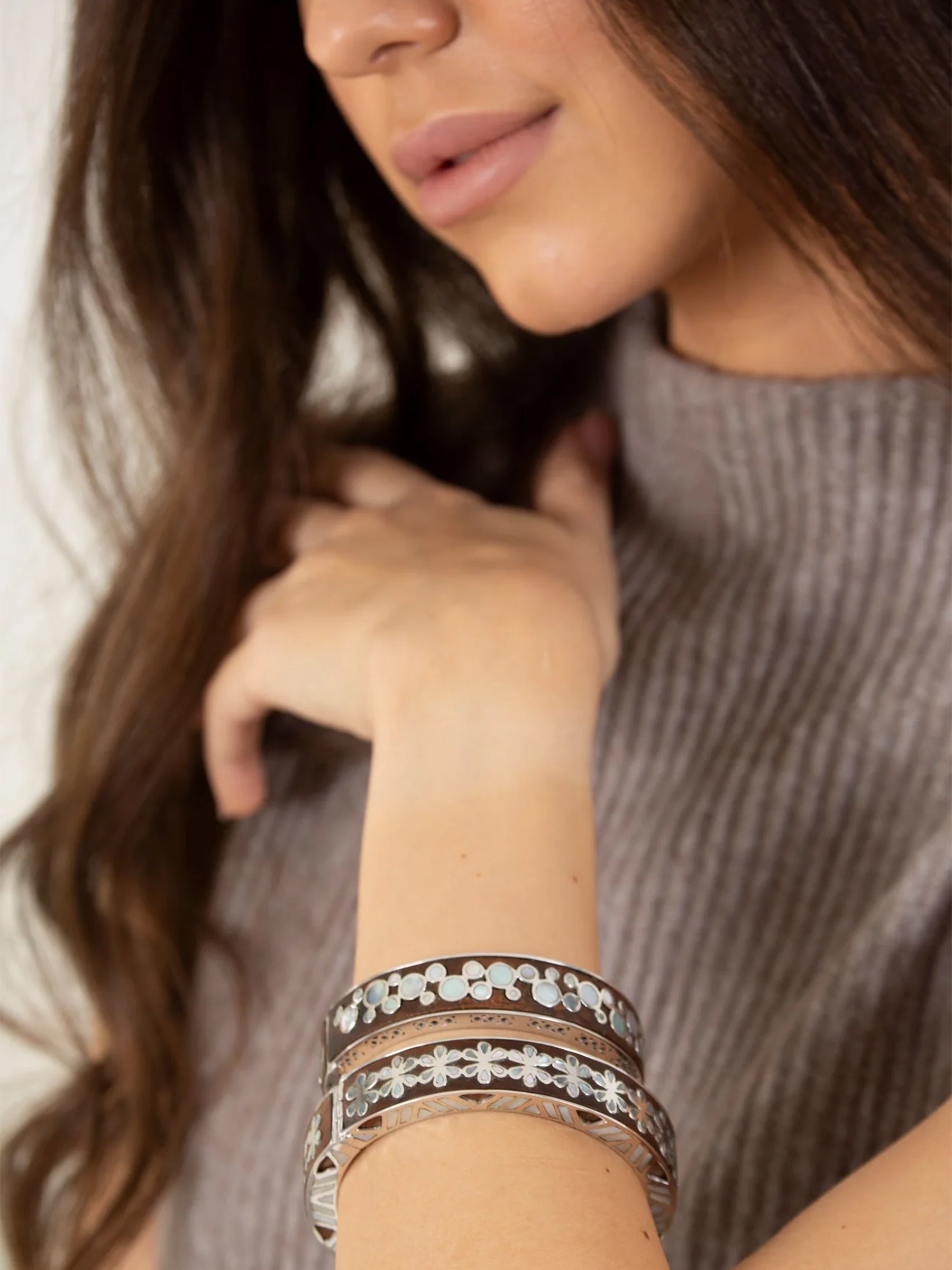 Model wearing Zanobia and Cleopatra mother of pearl bracelets in sterling silver with wood inlay on wrist