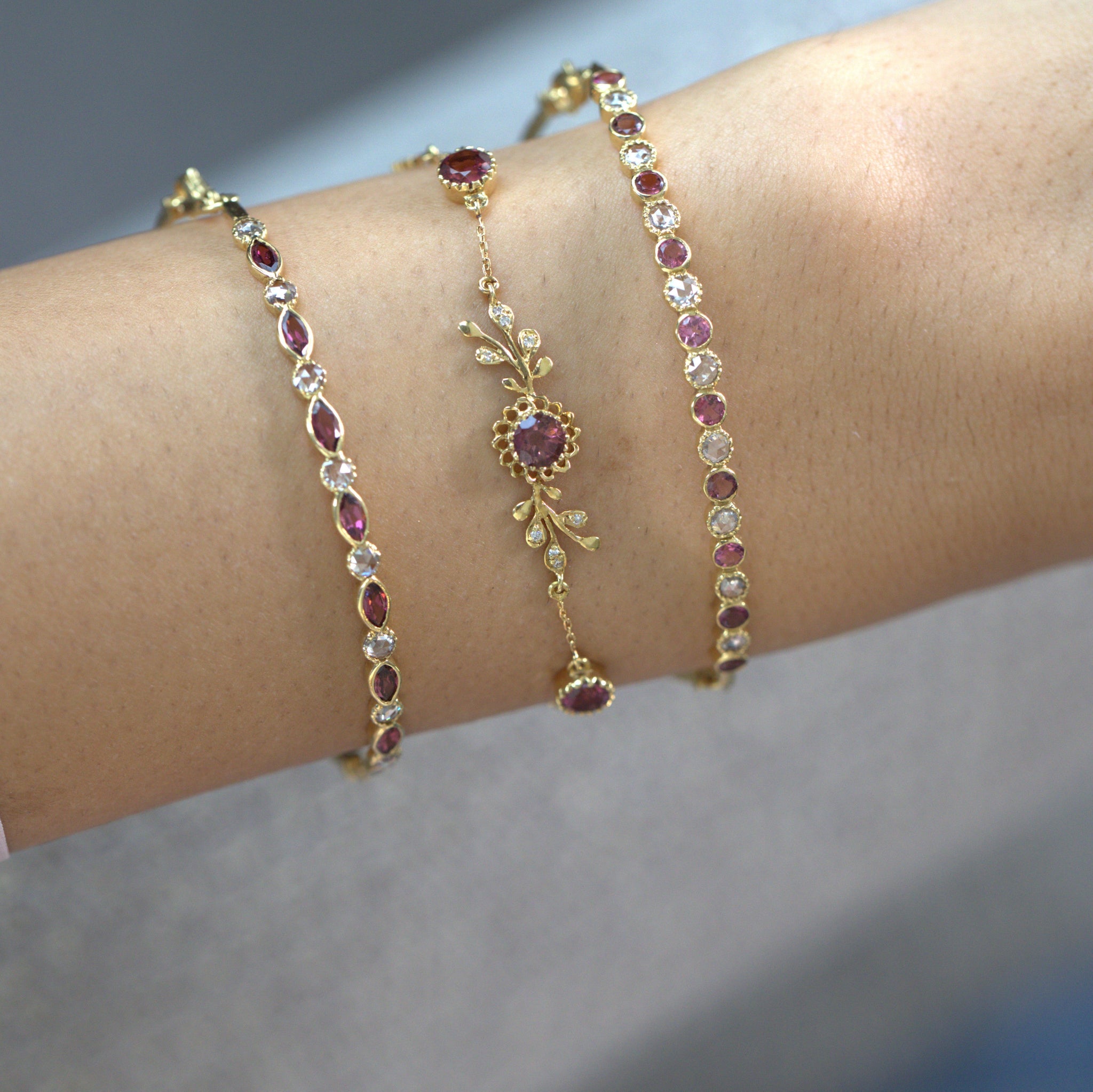 Close-up of a model’s wrist wearing stackable 18k gold bracelets with pink tourmalines and diamonds