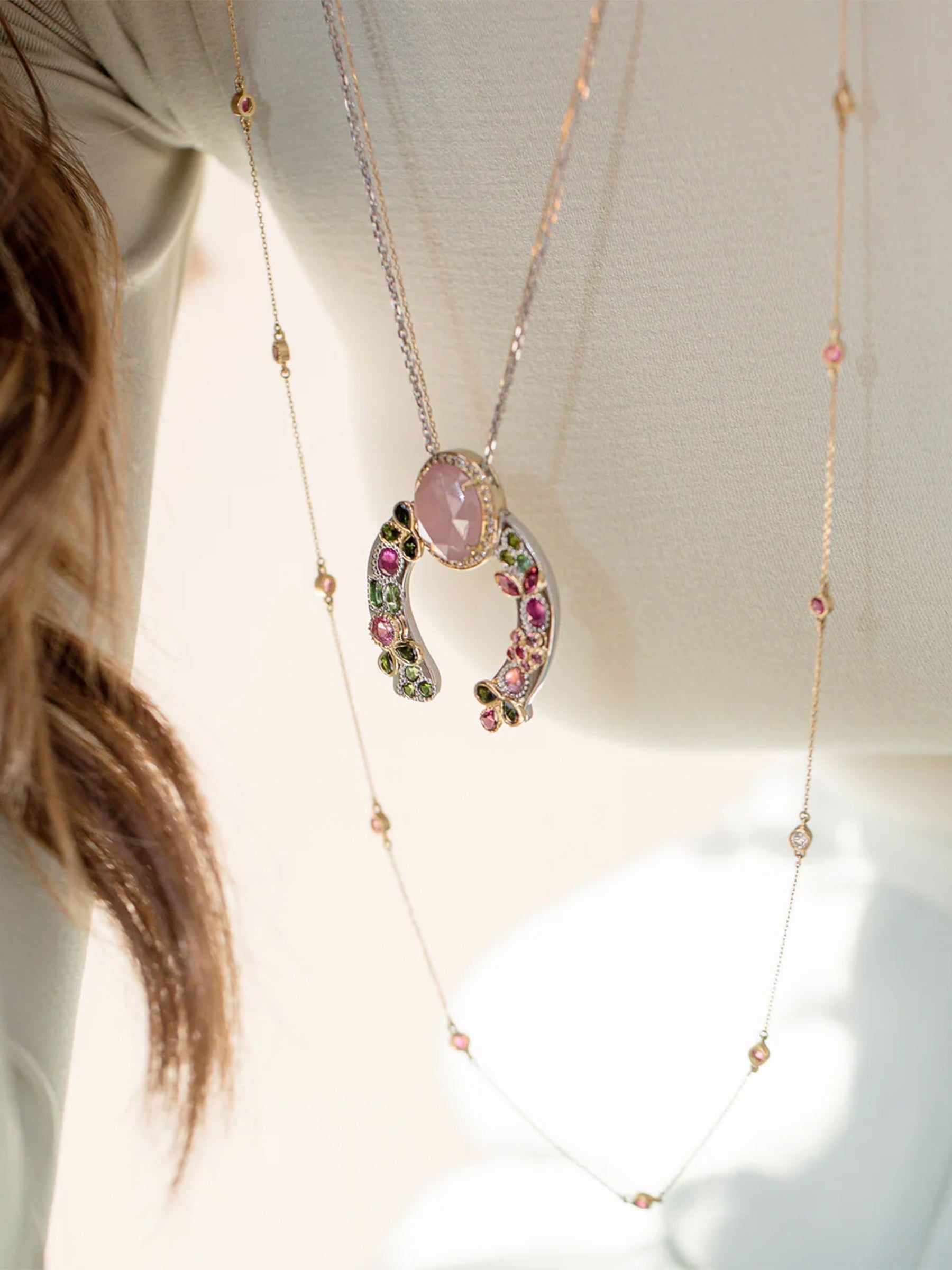 on-model layered jewelry look featuring the horseshoe pink sapphire necklace with tourmaline accents, diamond crown, and gold leaf detailing.