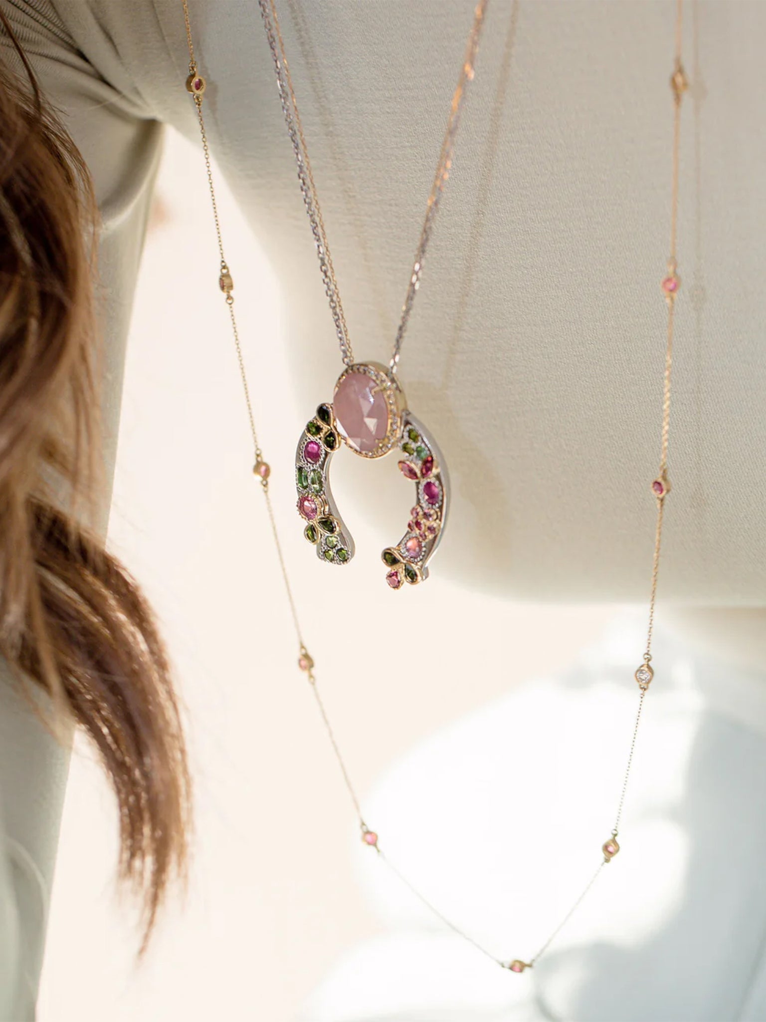 on-model layered jewelry look featuring the horseshoe pink sapphire necklace with tourmaline accents, diamond crown, and gold leaf detailing.