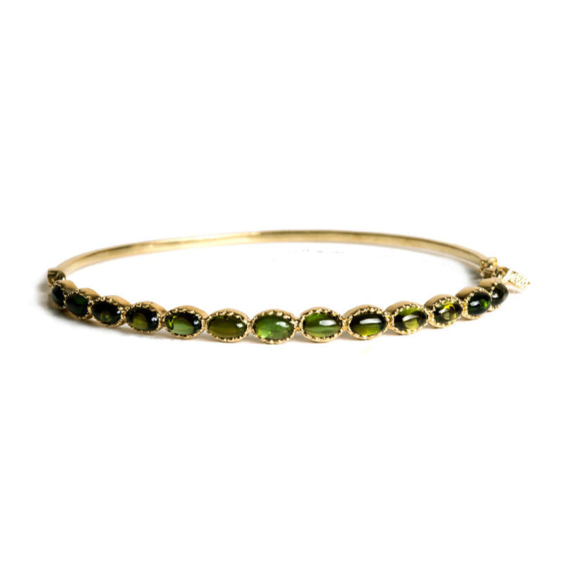 Gold bracelet with green cabochon tourmaline gemstones on a white background