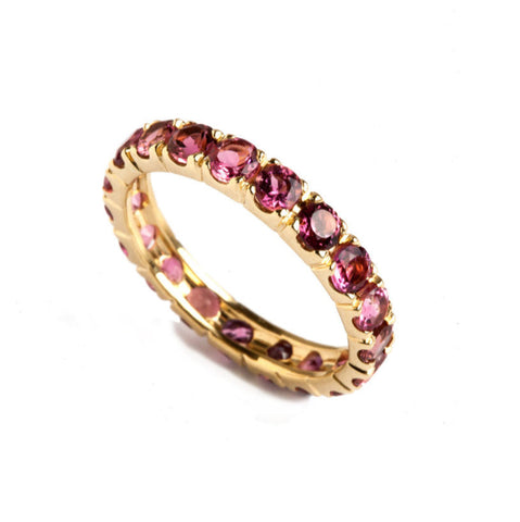 gold pink round tourmaline eternity ring on a white background