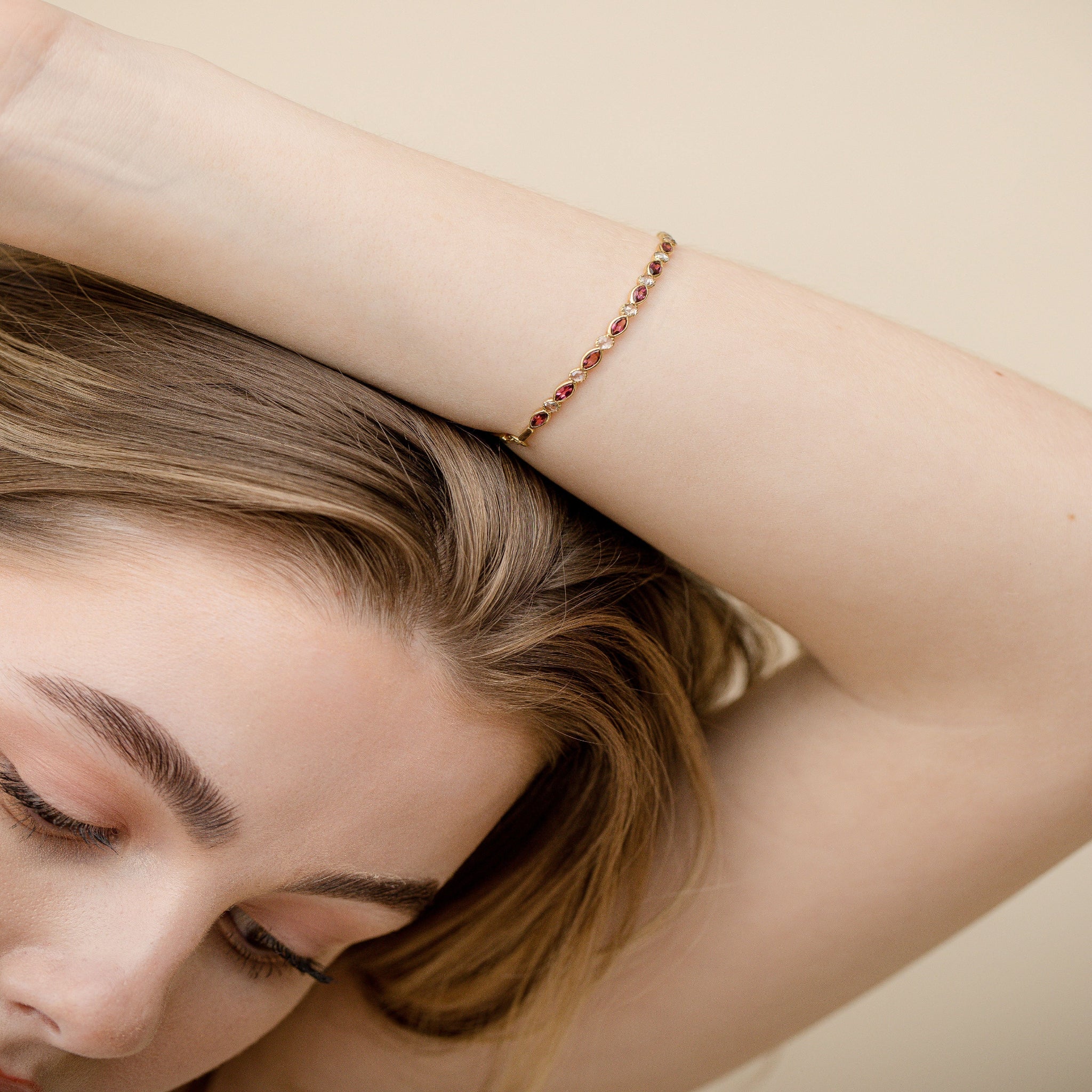 Model wearing gold bracelet with pink marquise tourmalines and rose-cut diamonds on her hand